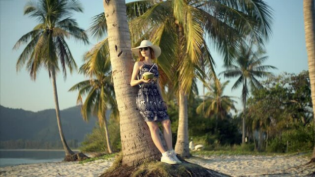 Young Woman Happy with Coconut Cocktail on a Tropical Island. Slow Wind. Still Picture with Moving Dress. Looping. Cinemagraph