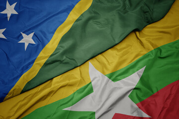 waving colorful flag of myanmar and national flag of Solomon Islands .