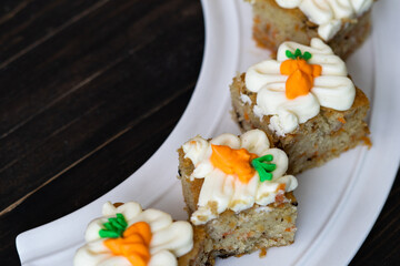 pieces of carrot cakes squares with walnuts and icing cream on a wooden background. selective focus.