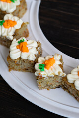 pieces of carrot cakes squares with walnuts and icing cream on a wooden background. selective focus.