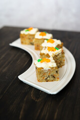 pieces of carrot cakes squares with walnuts and icing cream on a wooden background. selective focus.