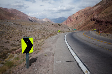 Sharp turn warning sign on mountain road. Highway road in Andes Mountains. Mendoza province, Argentina