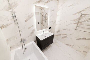 Bright bathroom in housing, large bath and mirror with backlight on the wall