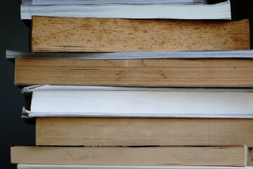 Side view of many old books stacked on the bookshelf after read.
