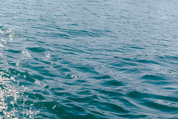 Small waves of azure sea with blurry background, used as a background or texture, soft focus