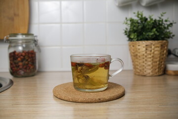 Brew tea from rosehip and lime blossom. Fruit tea. Brew in a cup. In the background of the kitchen-a pot with a flower. Bokeh. Blurred background.Cork board. 4k