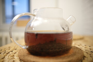 Close-up of a glass teapot with brewed tea. The process of brewing tea, tea ceremony, Boiling water. Leaves swirl. Strong tea. Blurred background. 4K