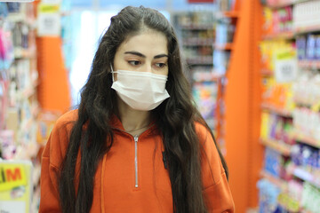 Young  woman wearing face mask push shopping cart in suppermarket. Shopping during the coronavirus Covid-19 pandemic.