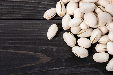 Pile of pistachios in the peel close-up on a wooden table. Selective focus