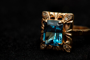 Gold ring with big blue gem and smaller diamonds.