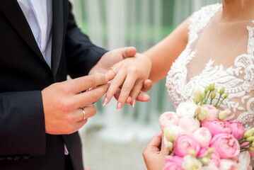 Obraz na płótnie Canvas bride putting on wedding ring on groom's finger