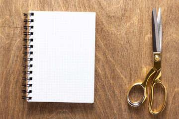 tailor or sewing scissors and notebook on wooden table background