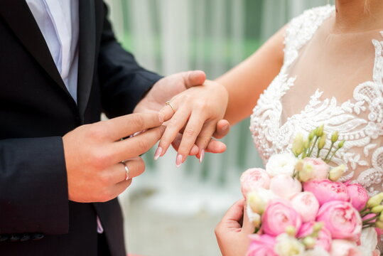 bride putting on wedding ring on groom's finger