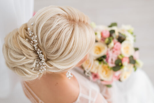 Hairstyle of the bride. A low bun on her blond hair. Rear and top view