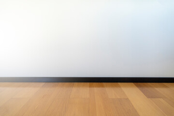 Empty room with wooden floating laminate flooring. House interior, wide bedroom or living room space. Newly recently painted new apartment or house. Wood floor. Real state and property management