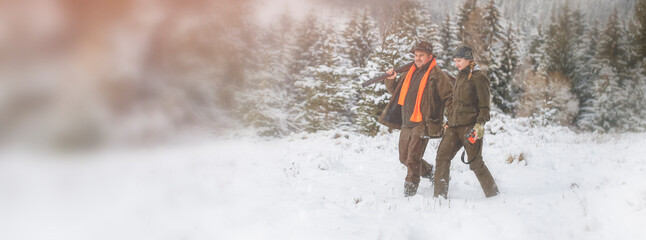 A young hunter woman with her husband in a snowy forest. They're on the hunt. Winter hunting...