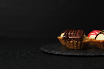 Selective focus of homemade chocolate cheese tart on slate plate on dark background.
