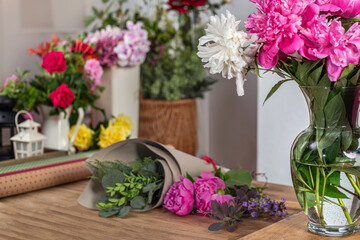 Crop view saller glass vase with blooming peonies. Floristic business. Arrangement of bouquets