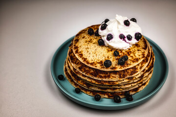 A stack of pancakes on teal plate with blueberries