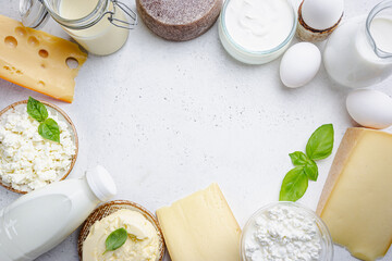 Fresh dairy products, milk, cottage cheese, eggs, yogurt, sour cream and butter on white table, top...