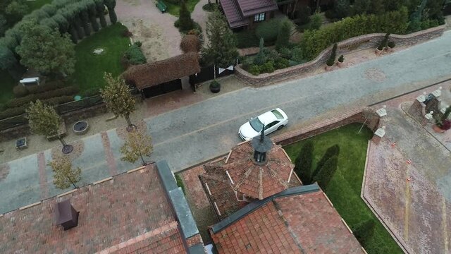 Modern white car pulls up on the road to restaurant building. Shooting from air