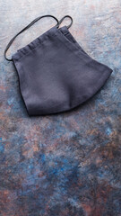 Handmade black protective mask on a dark background. Antivirus reusable face mask on the table. Copy space. Top view