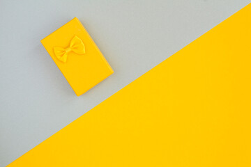 Top view of yellow gift box with bow on the two-tone surface