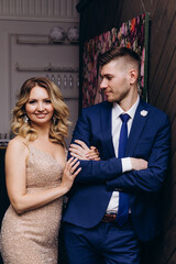 Photoshoot of the bride and groom in the studio. Beige dress and blue suit.