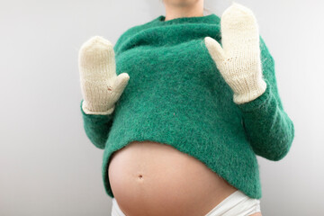 Pregnant woman in a woolen sweater and warm mittens
