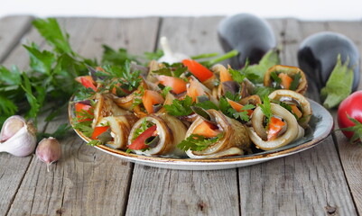Food background. Dish of tomatoes wrapped in fried eggplant wedges. Vegetable rolls with spicy grass and fresh vegetables on a wooden background.