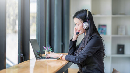 Obraz premium Portrait of happy smiling female call center operator working on computer in office.