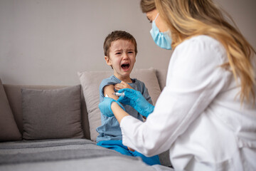 Boy getting a vaccine. A doctor giving a child an injection at home. Little boy getting vaccinated...