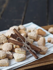 Homemade shortbread cookies sprinkled with sugar with cinnamon sticks on a kitchen board on a wooden background. Confectionery background.