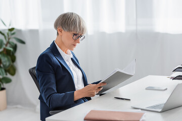 middle aged team leader in glasses looking at folder with documents