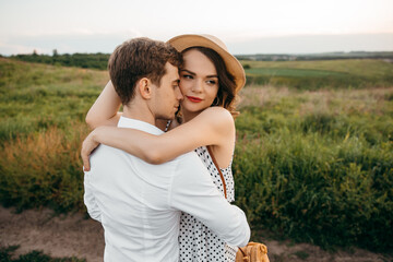 A loving young couple have fun fooling around and hugging on the background of nature