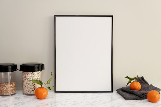 Black vertical frame mockup for kitchen wall art, blank frame on kitchen table.