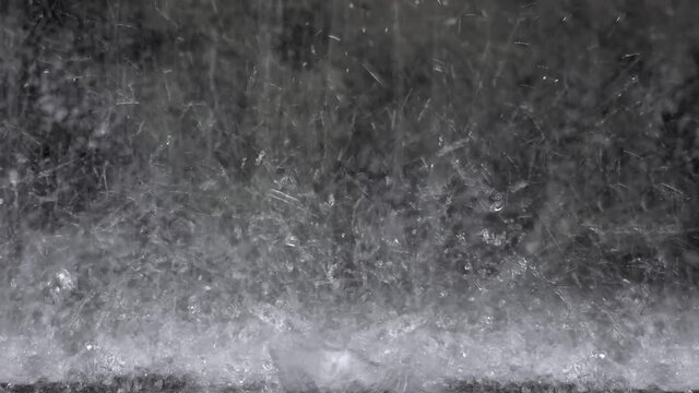 Heavy downpour on a bitumen road. Closeup.