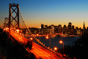 Fototapeta na wymiar The sun sets behind the San Francisco skyline and the Bay Bridge