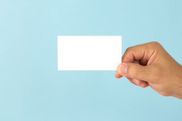 Businessman hand holding blank business card on light blue background