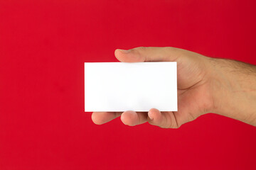 Businessman hand holding blank business card on red background