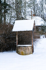 old water well in winter whose roof is snowy white