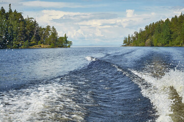 sky with clouds over the water. a trace of a boat on the water surface, waves.