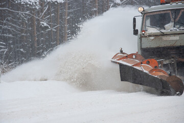 Snow blowing out from under the bucket of a snowblower