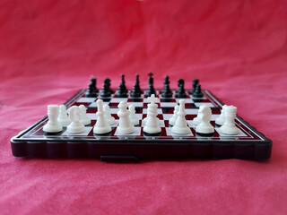 Magnetic chess on a red background. Recreation concept, sports intellectual game