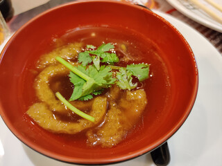 Close up of braised fish maw in red gravy serving in red bowl. Traditional Chinese food. Popular in Thailand