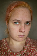 Close-up portrait of a girl with orange hair without makeup and skin retouching.