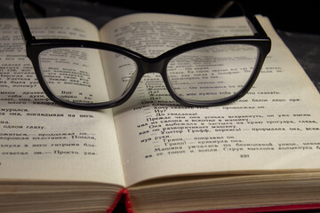 The glasses are on the book. Composition glasses and book