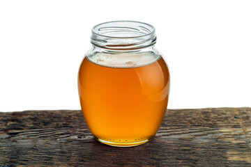 Round glass jar with freshly vegetable oil on the background of rough wood texture.