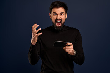 You will have problems man. Portrait of angry confused aggressive in bad mood guy shouting threatening, man holding mobile phone and screaming at camera, isolated on Pacific Blue background