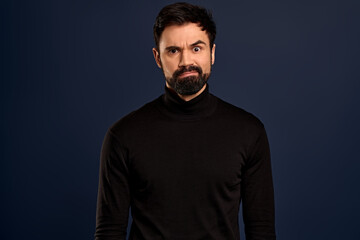 Obraz premium Freak-out shocked handsome bearded man, cringe from something disgusting or awful, grimacing alarmed, frowning make troubled, frustrated expression, standing worried over Pacific Blue background